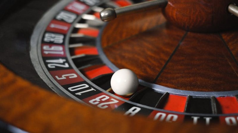 Detailed close-up image of roulette wheel highlighting numbers and spinning ball in a casino setting.