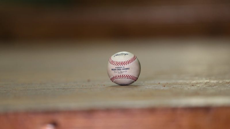 Close-up of a baseball on a wooden floor, highlighting sports equipment and leisure.